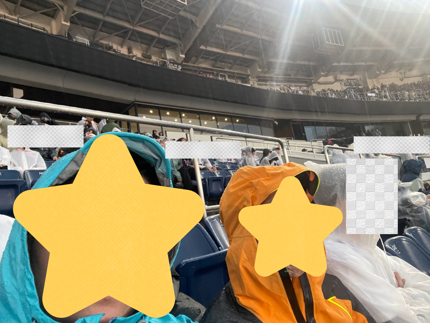 ZOZOマリンスタジアムのスタンド席で、雨の中レインウェアを着た2人